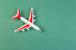 © Nana_studio - plastic model of an airplane with red wings. tourism and travel concept. green background top view