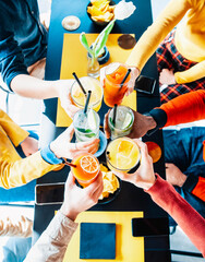 Wall Mural - Multicultural friends cheering and drinking cocktails at bar restaurant - Millennials people having fun at holiday party