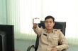 © ULTRAPOK - A Thai government officer, Civil servant showing his government official identification card.