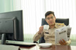 © ULTRAPOK - A Thai government officer, Civil servant is reading the newspaper and drinking coffee in the office.