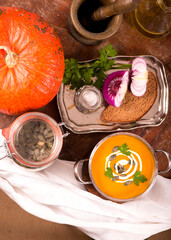 Wall Mural - Bowl of pumpkin soup on rustic wooden background