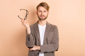 Photo of serious charming young guy wear jacket arm spectacles isolated beige color background