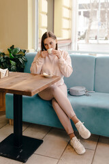 Wall Mural - Woman drinking coffee while sitting on a cafe terrace