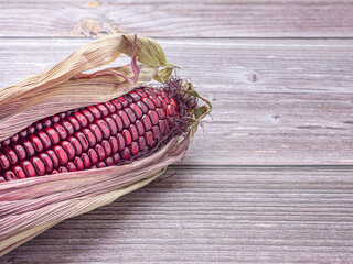 Wall Mural - Side view of purple corn or Siam ruby queen isolated on a wooden table. Space for text. Vegan fruit and healthy fruits concept