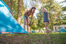 Cute Blonde Girl Helping Around Tent Pitch At Camping Resort.
