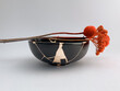 Black Kintsugi bowl with red flowers, Japanese restoration technique with gold scars, the beauty of imperfection