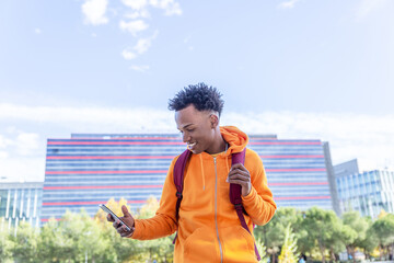 dark skinned boy with wide smile looks at his mobile phone