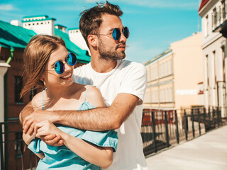 Portrait of smiling beautiful woman and her handsome boyfriend. Woman in casual summer jeans dress. Happy cheerful family. Female having fun. Couple posing on the street background in sunglasses