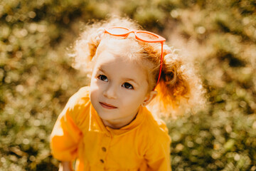 Portrait photos caucasian kid girls aged 2 to 4 years with curly hair, cute face, smiling, looking healthy and cute, with green bokeh background