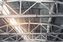 Old Abandoned Decay Industry Factory Or Plant Roof Ceiling Interior With Concrete And Steel Metal Construction Frame Beams. Sunlight Warm Sun Through Rooftop Window. Dark Grungy Industrial Background