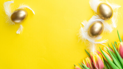 Wall Mural - Easter egg. Happy Easter decoration: Golden eggs in basket with spring tulips, white feathers on pastel yellow background. Traditional decoration in sun light. Top view.