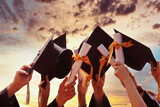 Fototapeta  - International students in mortar boards and bachelor gowns with diplomas.