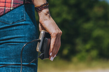 Wall Mural - Close-up, Power Bank with a phone in the girl's hand. Against the backdrop of nature.