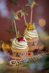 Canvas Print - Christmas cupcakes with vanilla frosting, cranberries and rosemary on wooden background. Selective focus