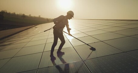 Wall Mural - cinematic shot of maintenance assistance technical worker in uniform is cleaning photovoltaic solar 