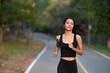 © Prathankarnpap - Athletic woman running in city park at the evening.