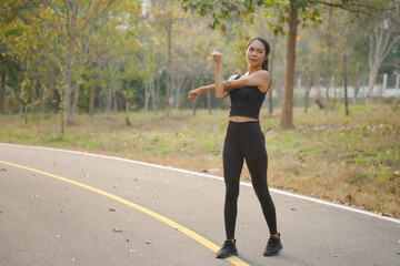 Happy sportswoman stretching arms before workout outdoor.