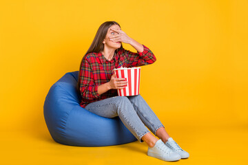 Poster - Full size photo of young scared afraid girl cover face sit armchair watch horror movie isolated on yellow color background