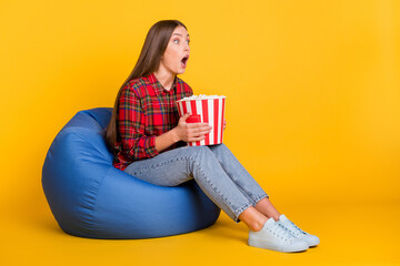 Poster - Full size profile photo of impressed brunette long hairdo lady hold pop corn wear red shirt jeans lie on bag isolated on yellow background