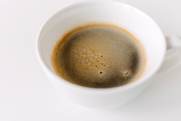 Closeup of a cup of black coffee on white table.