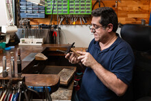 Foreground, Hammer Hammering A Silver Ring To Shape It In A Jewelry Workshop.