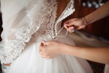 Wall Mural - The witness at the wedding helps to lace up the corset for the bride on the wedding dress. Girl's hands tighten the shoelaces on the dress. White dress with lace cherry