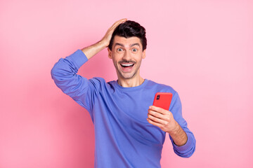 Poster - Photo of amazed astonished crazy young man hold hand head phone news isolated on pastel pink color background