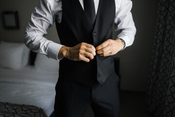 a man wears a black vest in a hotel room