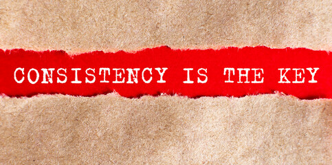 Consistency is The Key appearing behind torn paper on red background