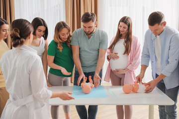 Poster - Future fathers and pregnant women learning how to swaddle baby at courses for expectant parents indoors