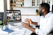 © Kateryna - Virtual meeting. Successful African American business man sits at work desk at home, looks at the computer screen, communicates on a video conference with his colleagues, discusses a business plan
