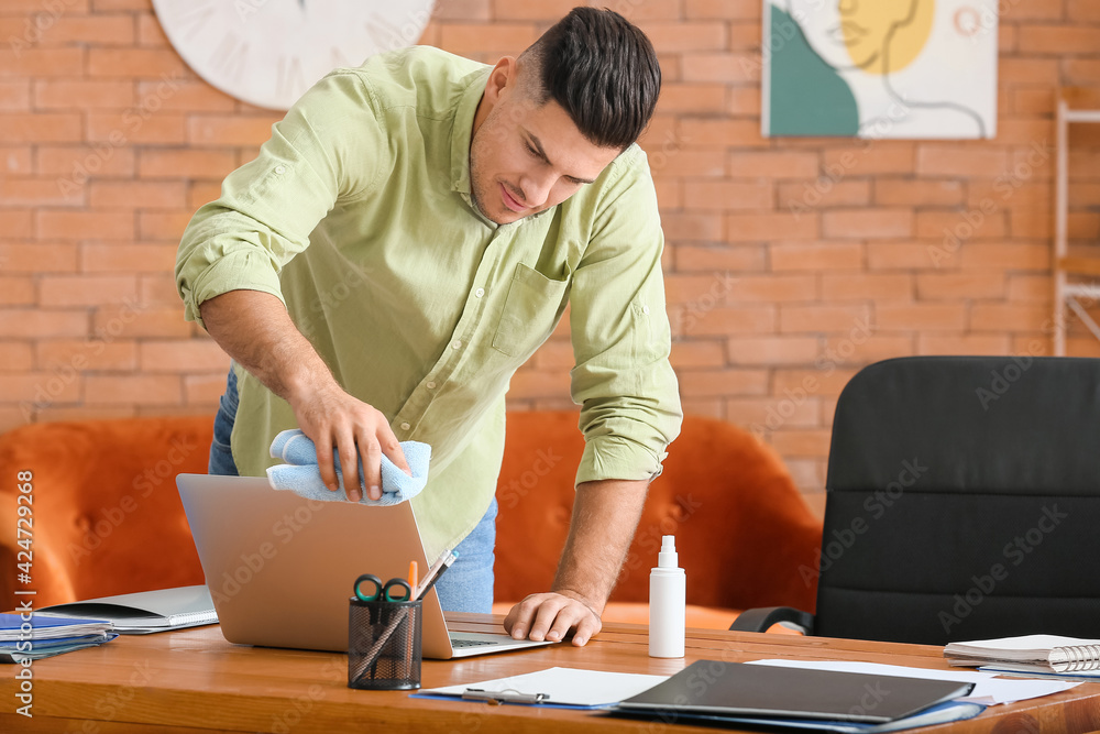 Young man cleaning laptop at home