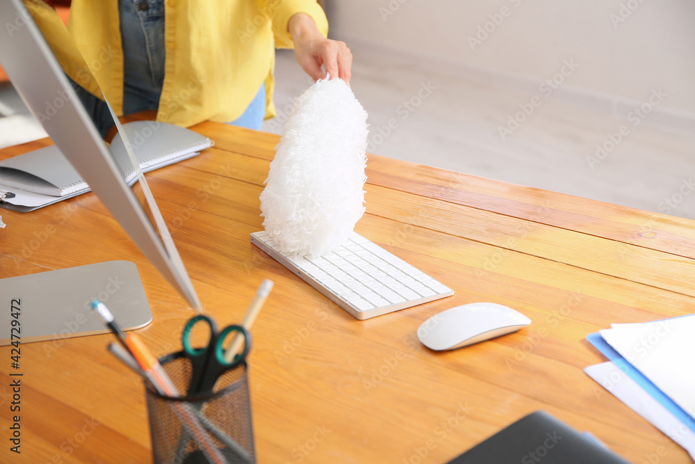 Young woman cleaning computer at home