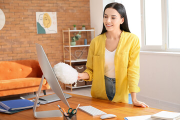Young woman cleaning computer at home
