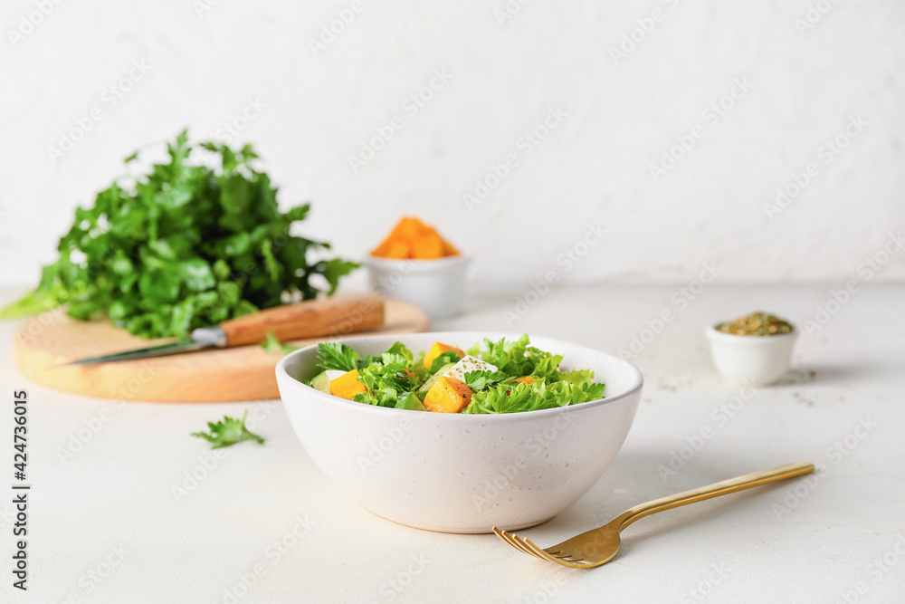 Bowl of fresh salad with vegetables on light background