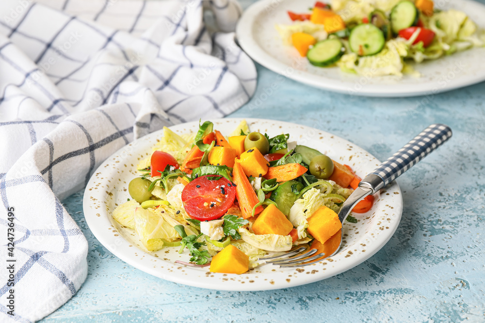 Plate of fresh salad with vegetables on color background