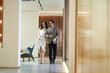 Asian happy upscale couple walking in hallway hand in hand smiling