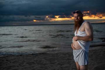 Wall Mural - Humorous portrait of a brutal man posing on the beach at sunset