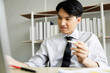 © SHUTTER DIN - young asian business man sitting and holding pencil on hand looking tablet in office