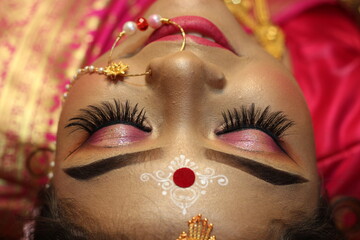 Closeup Portrait of an beautiful woman Indian model in Bridal look with heavy gold jewelry and red sari.