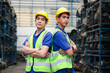 © Stella - Portrait of two industrial engineer workers man wearing helmet with arms crossed, standing at manufacturing plant factory with many engine parts as blurred background