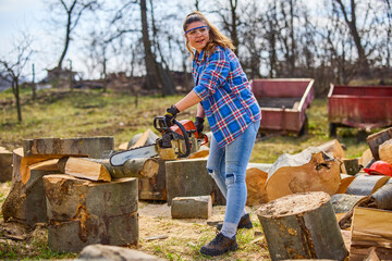 Wall Mural - Young Woman using chainsaw to cut a log for firewood.