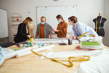 Wall Mural - Three people watching a dress designer cutting fabric