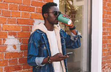 Portrait of stylish young african man drinking coffee on a city street