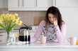 © Tomsickova - Tired mother, trying to pour coffee in the morning. Woman lying on kitchen table after sleepless night