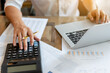 © C_Production - Businessman pressing on calculator for calculating cost estimating with laptop.