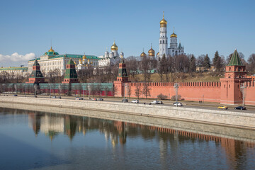 The beautiful Moscow Kremlin on the banks of the river. Red brick towers. Blue sky. Sunny day. Ancient architecture.