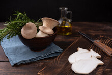 Three Raw King Oyster Mushrooms, Rosemary Sprigs In A Bowl On A Dark Wooden Background.