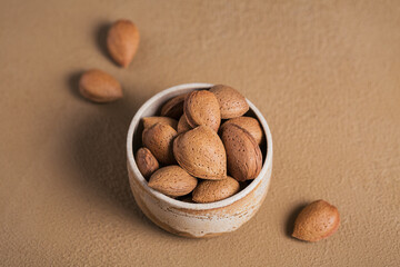 Wall Mural - Pile of Almond nuts in a bowl on a brown background