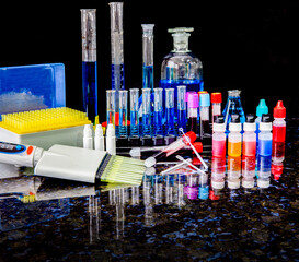 Laboratory material on the dark surface, test tubes, automatic pipette, precision glassware, flasks, tubes with blood. Science working for the coronavirus pandemic